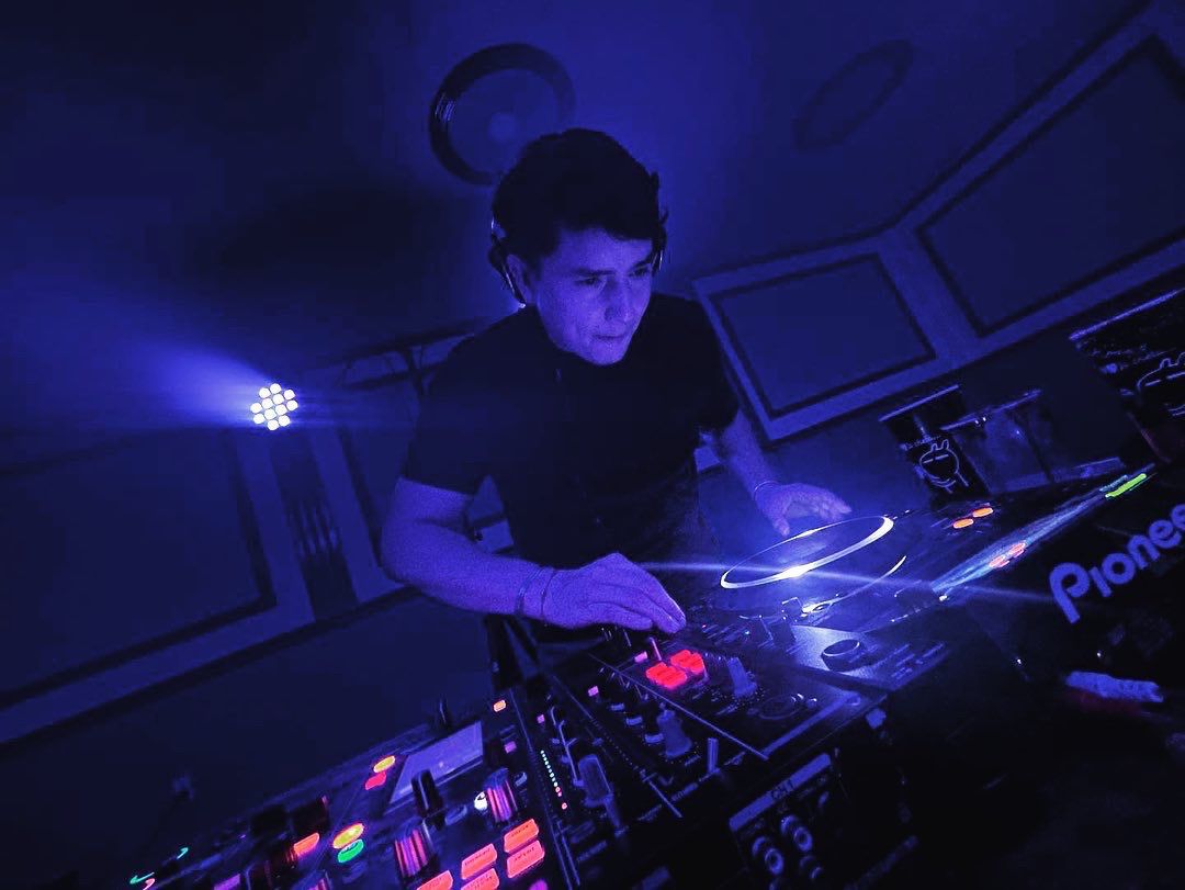 DJ profesional con cabina Pioneer e iluminación