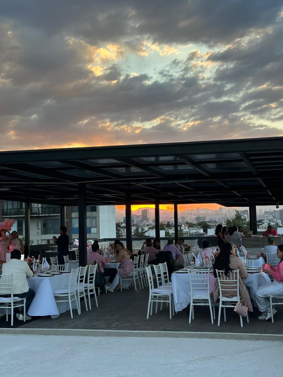Evento en rooftop con mesas blancas al atardecer